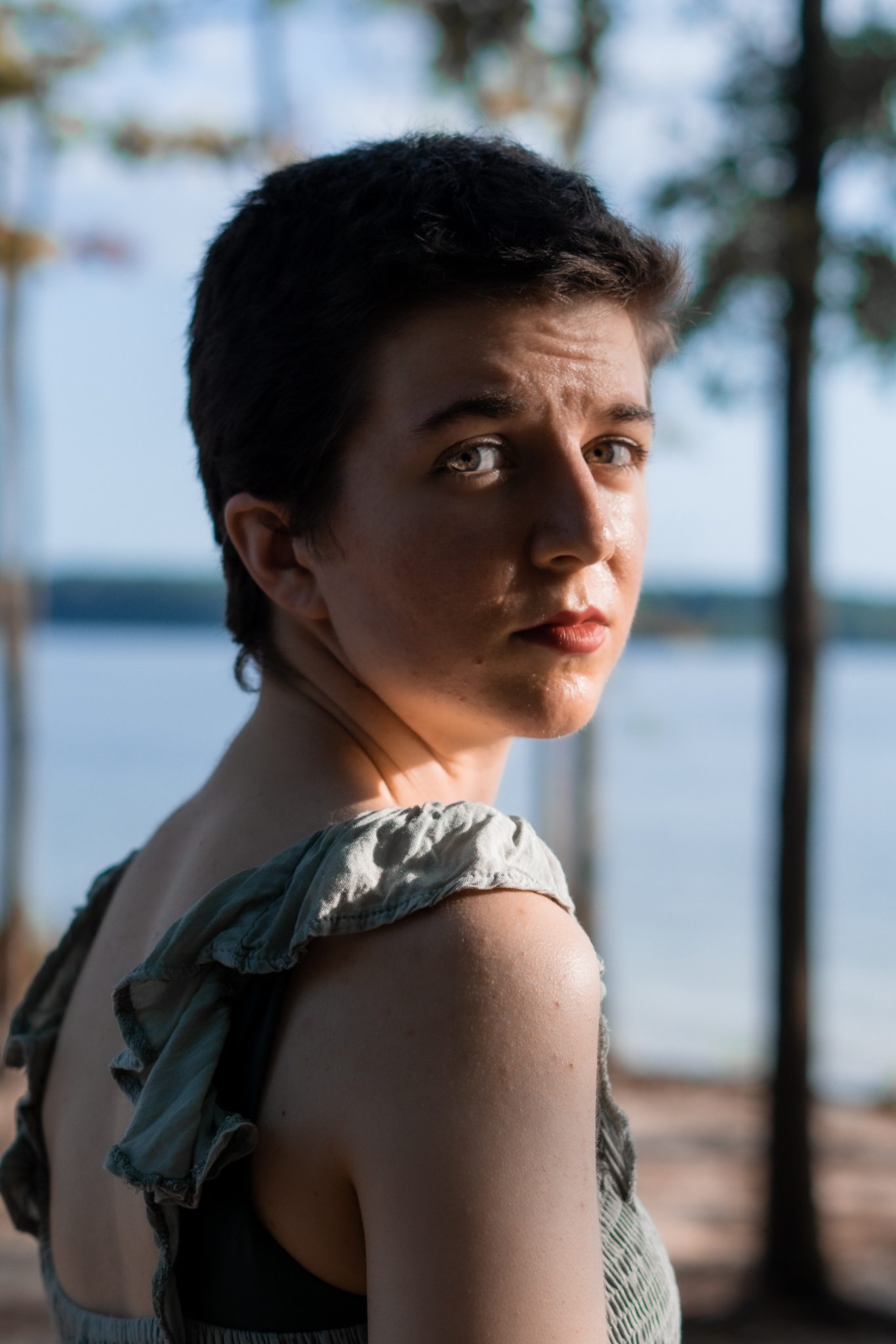 Headshot of white person with short dark hair, looking over shoulder at the camera. 